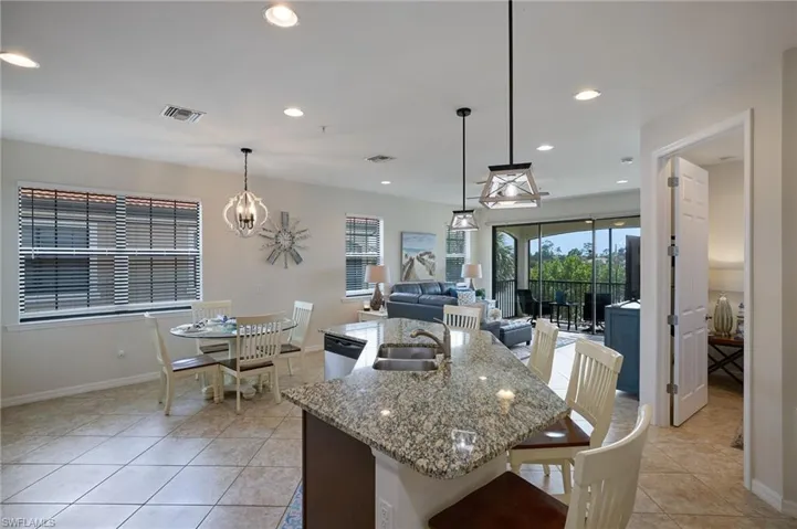 Kitchen with visible vents, dishwasher, a sink, light stone counters, and an inviting chandelier