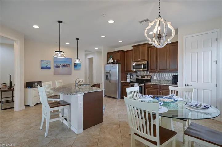 Kitchen featuring decorative backsplash, visible vents, a chandelier, stainless steel appliances, and an island with sink