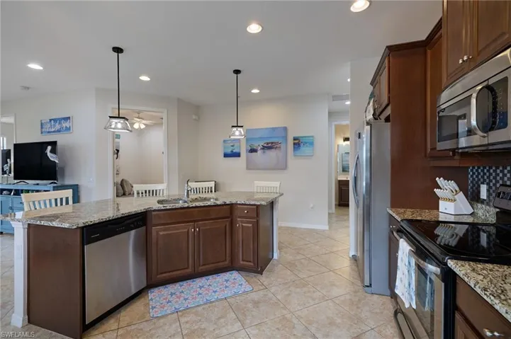 Kitchen with a sink, stainless steel appliances, light stone counters, and recessed lighting