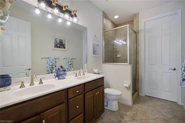 Bathroom featuring double vanity, a sink, a stall shower, and tile patterned floors