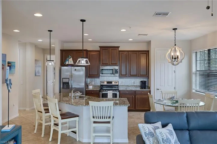 Kitchen with visible vents, a kitchen bar, tasteful backsplash, appliances with stainless steel finishes, and light tile patterned floors
