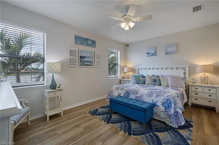 Bedroom with baseboards, ceiling fan, visible vents, and wood finished floors