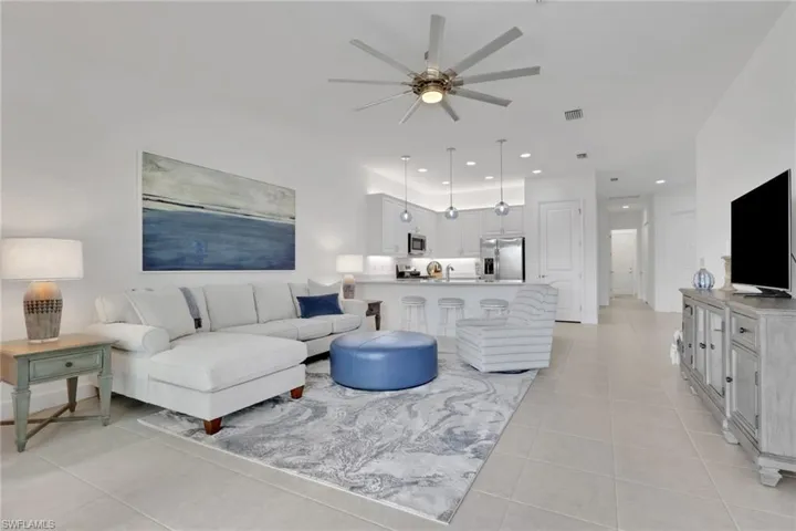 Open-concept living area featuring light-toned tile flooring, recessed lighting, and a contemporary ceiling fan