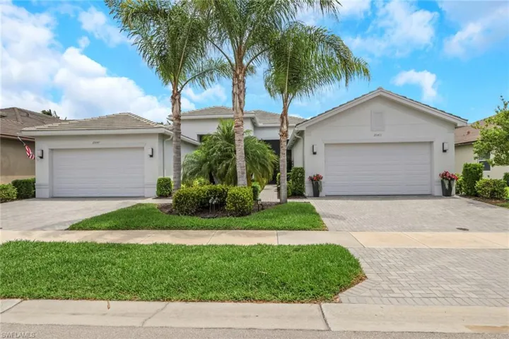 Contemporary stucco exterior featuring a tiled roof and two attached garages with paver driveways