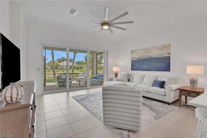 Spacious living area featuring large sliding glass doors opening to a screened lanai with outdoor seating