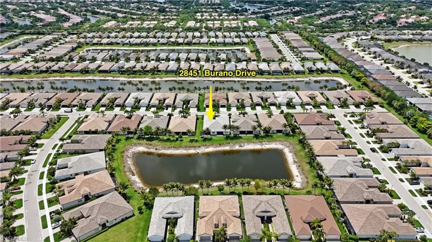 Aerial perspective of a residential community featuring a property with a water-facing backyard and surrounding homes with varied rooflines