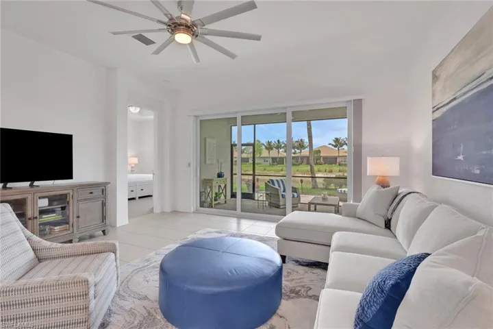 Spacious living area featuring neutral-toned tile flooring, a contemporary ceiling fan, and large sliding glass doors