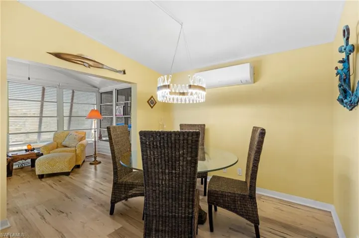 Dining area featuring a wall mounted air conditioner, wood-type flooring, and ornamental molding