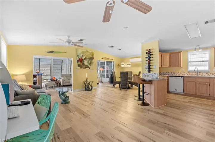 Living room featuring ceiling fan, light wood-style floors, and vaulted ceiling