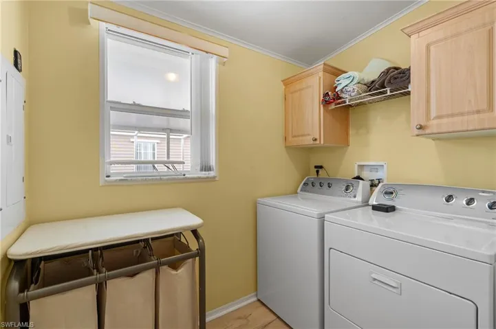Laundry room with light hardwood / wood-style floors, crown molding, cabinets, and independent washer and dryer