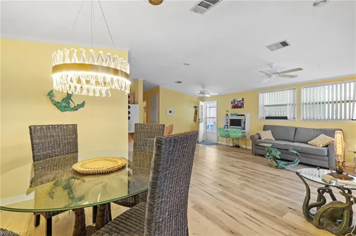 Dining area with ceiling fan, light wood-style floors, and ornamental molding