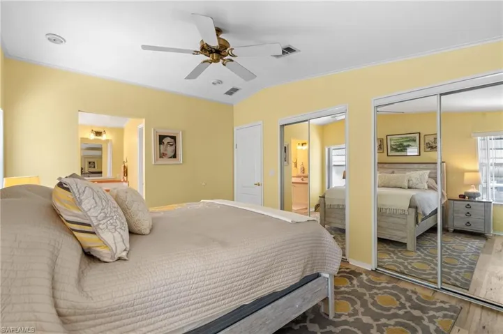 Bedroom featuring two closets, ceiling fan, crown molding, hardwood / wood-style flooring, and connected bathroom