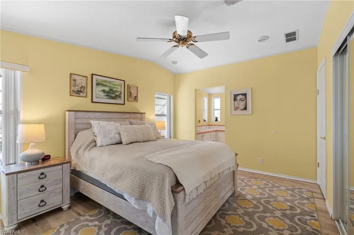 Bedroom featuring dark hardwood / wood-style floors, ceiling fan, lofted ceiling, and ensuite bathroom