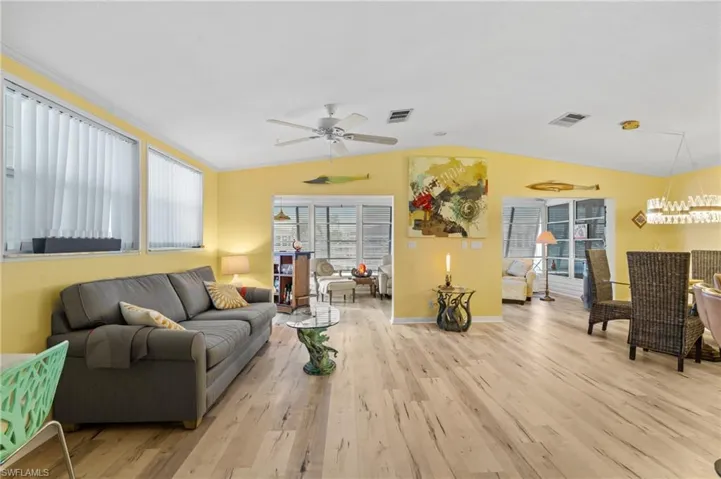 Living room featuring ceiling fan, light wood-style floors, and vaulted ceiling