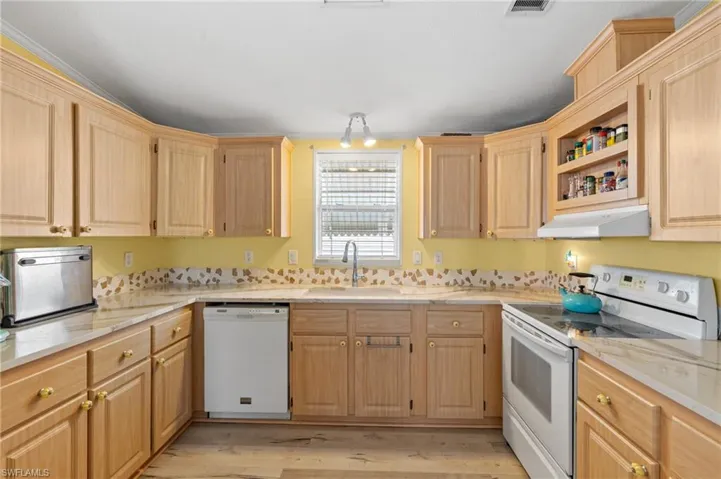 Kitchen featuring light wood-type flooring, light brown cabinets, white appliances, and sink