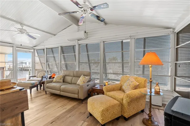 Sunroom featuring a wall mounted air conditioner, ceiling fan, a water view, and lofted ceiling