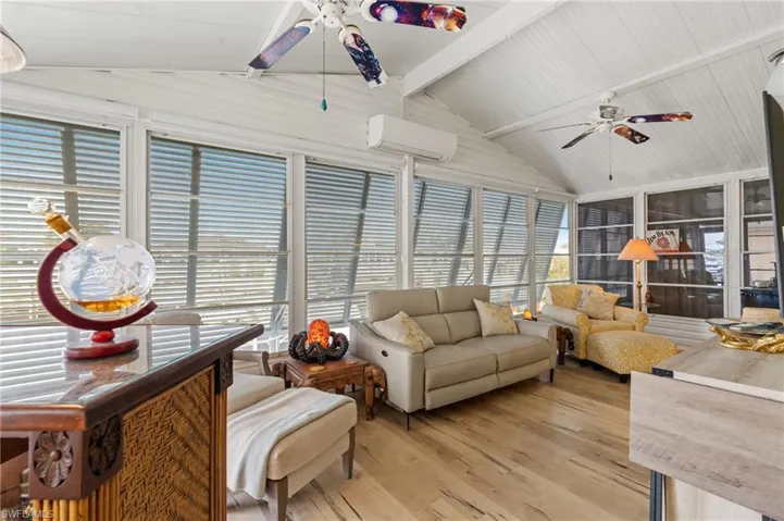 Sunroom featuring a wall mounted air conditioner, lofted ceiling with beams, and ceiling fan