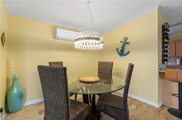 Dining room with light wood-style floors, an inviting chandelier, and crown molding