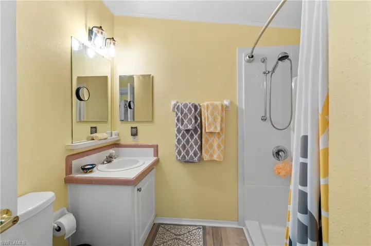 Bathroom featuring wood-type flooring, walk in shower, and ornamental molding