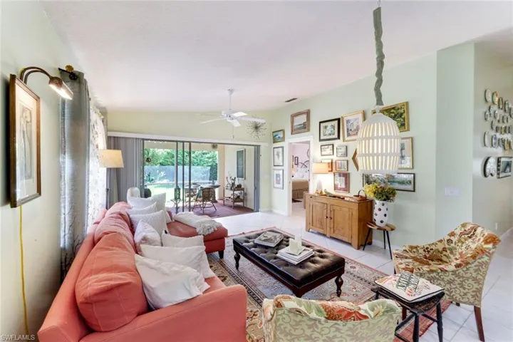 Living area with ceiling fan, light tile patterned floors, and lofted ceiling