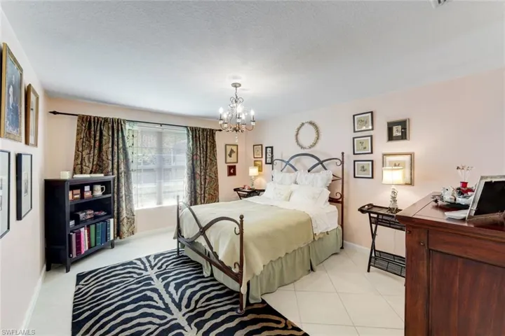 Bedroom with a chandelier, a textured ceiling, and light tile patterned flooring