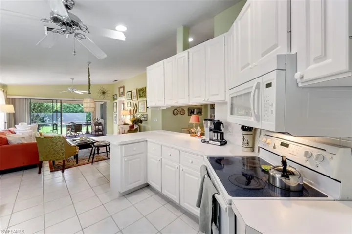 Kitchen featuring white appliances, a peninsula, open floor plan, and white cabinetry
