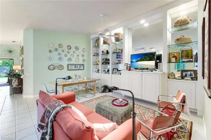 Living area with ceiling fan, light tile patterned floors, and built in features