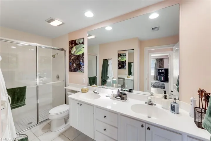 Bathroom with double vanity, a shower stall, tile patterned flooring, and recessed lighting