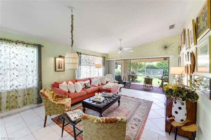 Living area featuring plenty of natural light, ceiling fan, light tile patterned flooring, and vaulted ceiling