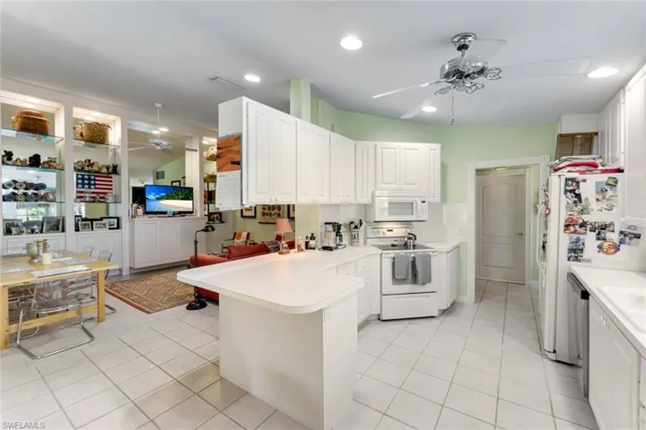 Kitchen featuring ceiling fan, a peninsula, white appliances, light countertops, and light tile patterned floors