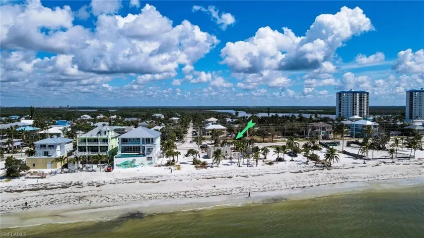 Birds eye view of property with a water view and a beach view