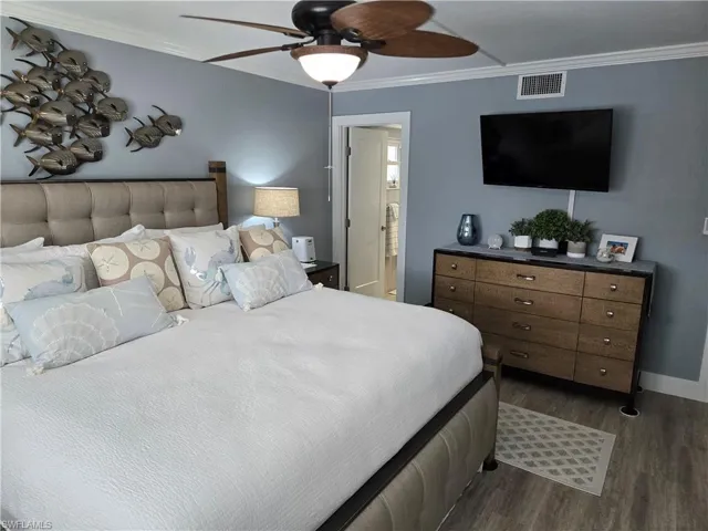 Bedroom featuring crown molding, dark hardwood / wood-style floors, ensuite bathroom, and ceiling fan