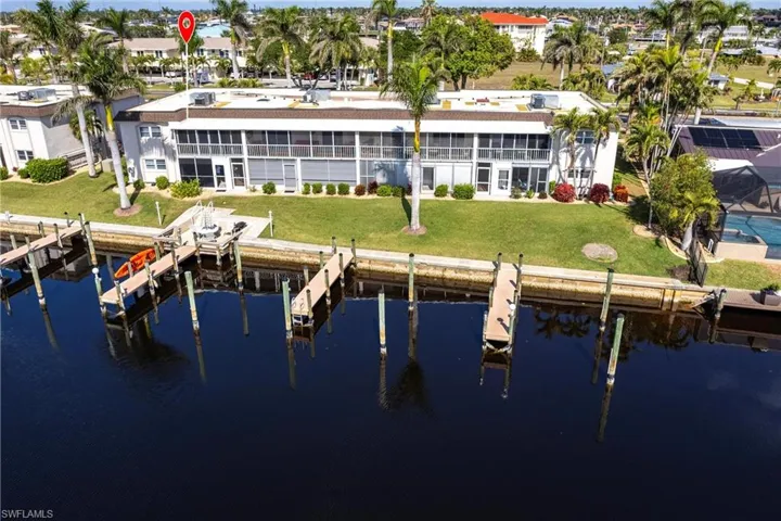 Back of house with a water view and a lawn