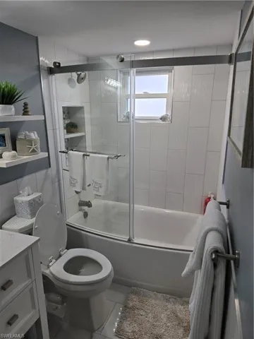Full bathroom featuring vanity, toilet, and combined bath / shower with glass door