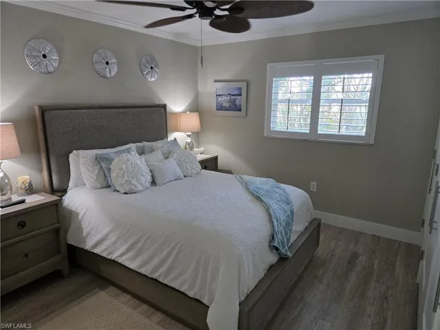 Bedroom with ornamental molding, dark hardwood / wood-style floors, and ceiling fan
