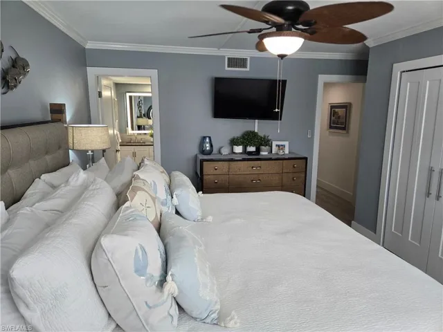 Bedroom with ensuite bath, ornamental molding, and ceiling fan