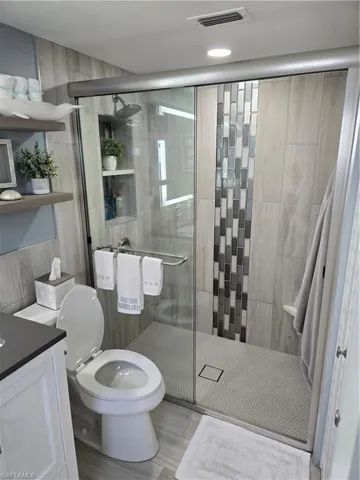Bathroom with vanity, toilet, and an enclosed shower