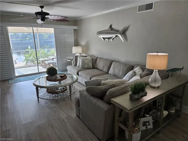 Living room with hardwood / wood-style flooring, ornamental molding, and ceiling fan