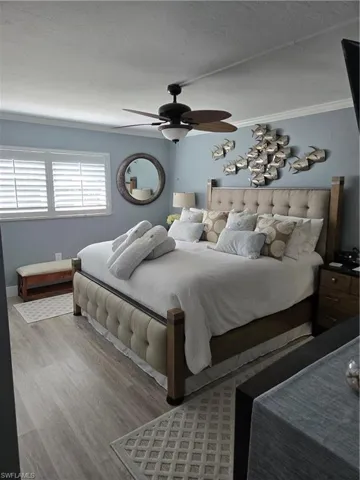 Bedroom with crown molding, ceiling fan, and light hardwood / wood-style floors