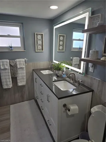 Bathroom featuring vanity, plenty of natural light, toilet, and tile walls