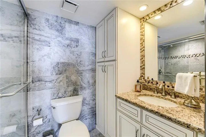 Bathroom featuring a granite-topped vanity with an undermount sink and brushed nickel faucet