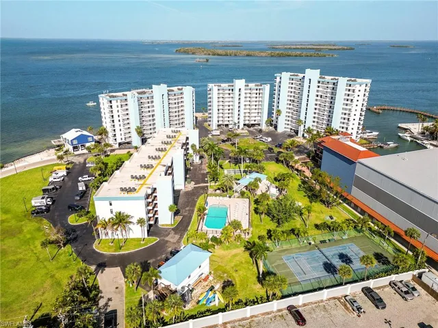 Waterfront multi-story buildings featuring balconies, a swimming pool, tennis court, and marina access
