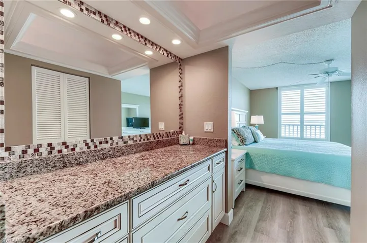 Extended vanity featuring a speckled countertop, a decorative tiled backsplash, and recessed lighting