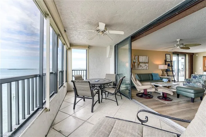 Enclosed balcony with tile flooring, featuring expansive water scenery and seamless access to the interior via sliding glass doors