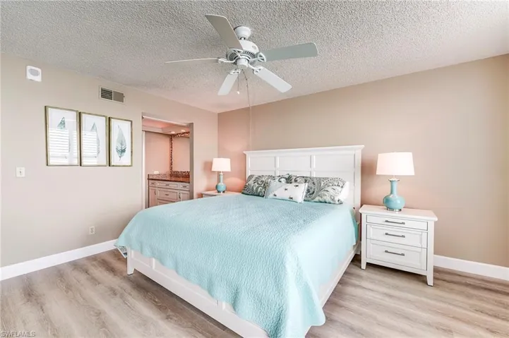 Bedroom featuring light wood-finish flooring, a white ceiling fan, and painted walls