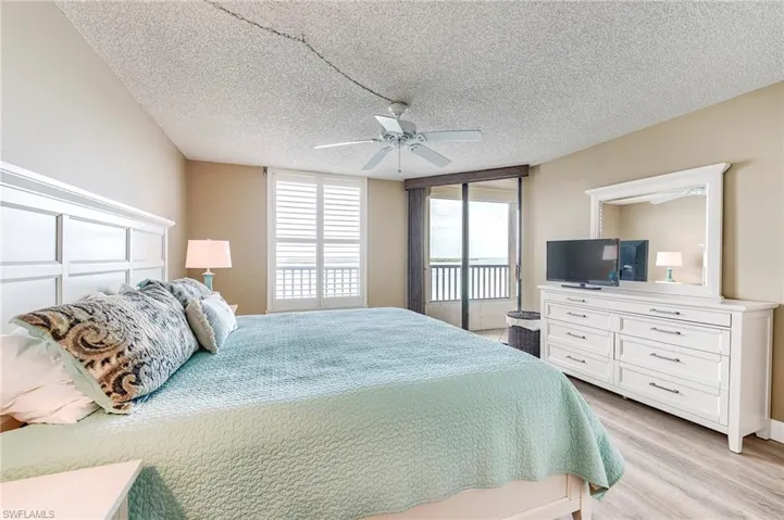 Bedroom featuring wood-finish flooring, a white paneled headboard, and neutral wall tones