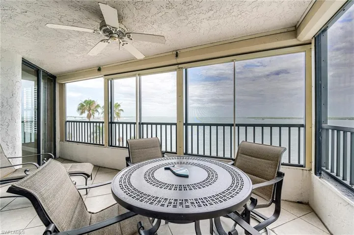 Enclosed balcony featuring large windows, a ceiling fan, and tile flooring