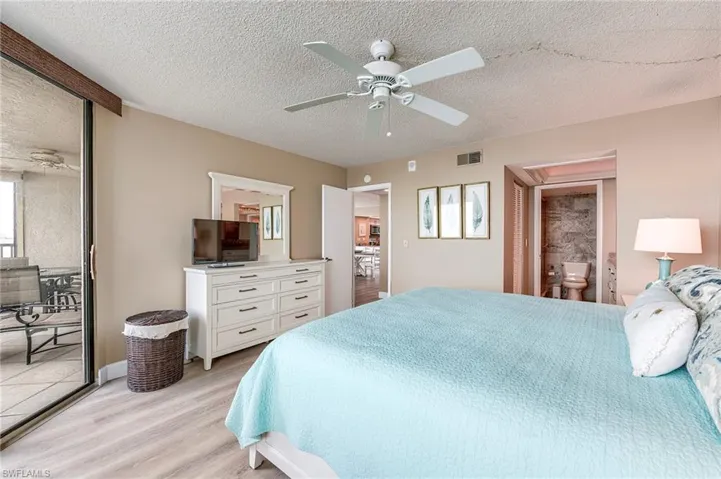 Bedroom featuring wood-finish flooring, a ceiling fan, and a sliding glass door opening to a private balcony