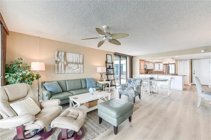 Open-concept living space featuring light wood-finish flooring, a ceiling fan, and sliding glass doors to the exterior
