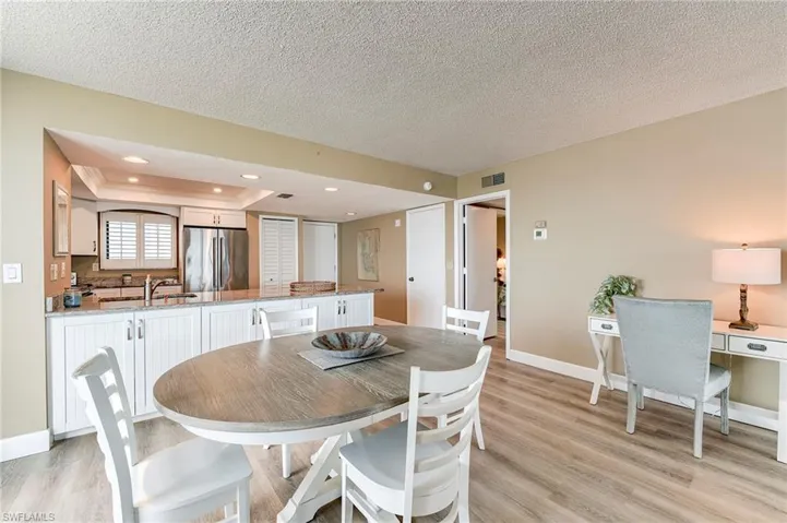 Kitchen featuring white cabinetry, granite countertops, stainless steel appliances, and a pass-through window with plantation shutters
